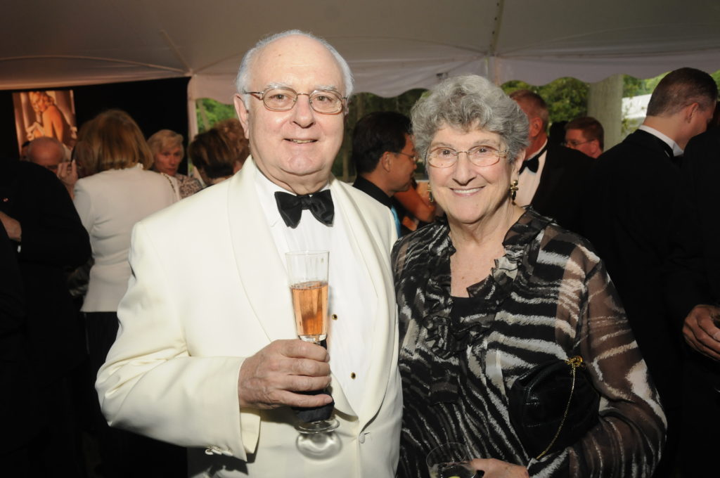 Ed and Elaine Schroeder standing side by side, Ed is holding a champagne flute at a Caramoor Opening Night Gala c. June 2010