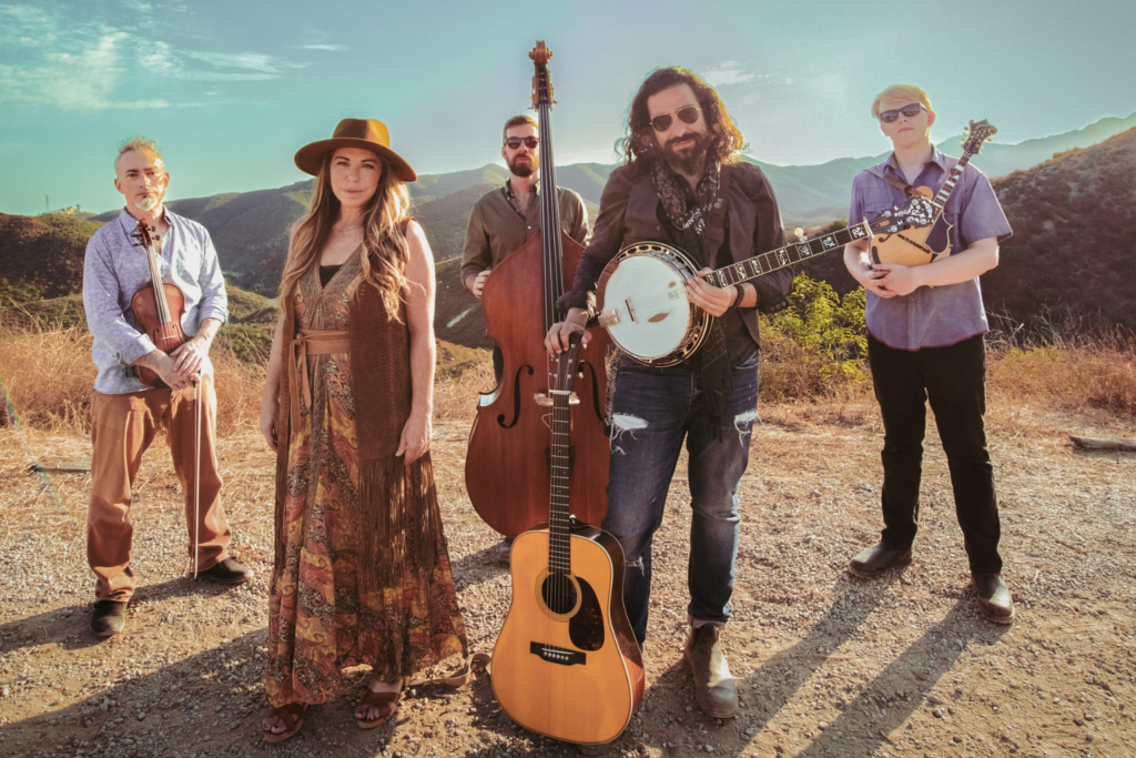 Nefesh Mountain poses atop a mountain with their instruments in hand.